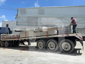 Plataforma de tráiler con carga de materiales de obra asegurados con cintas de sujeción