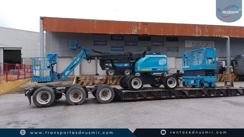 Transporte en plataforma de equipo elevador articulado y maquinaria pesada en patio industrial